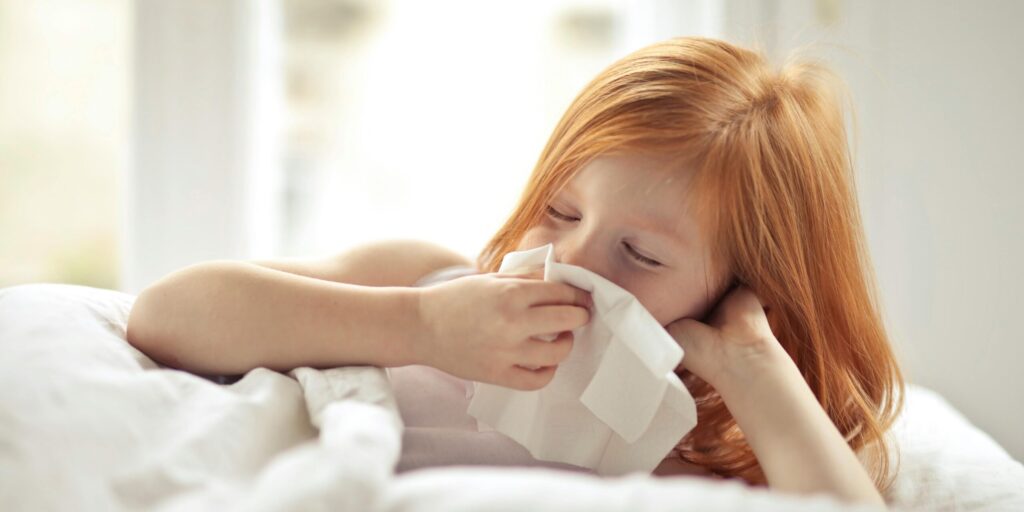 A Sick Girl Wiping Her Nose with Tissue
